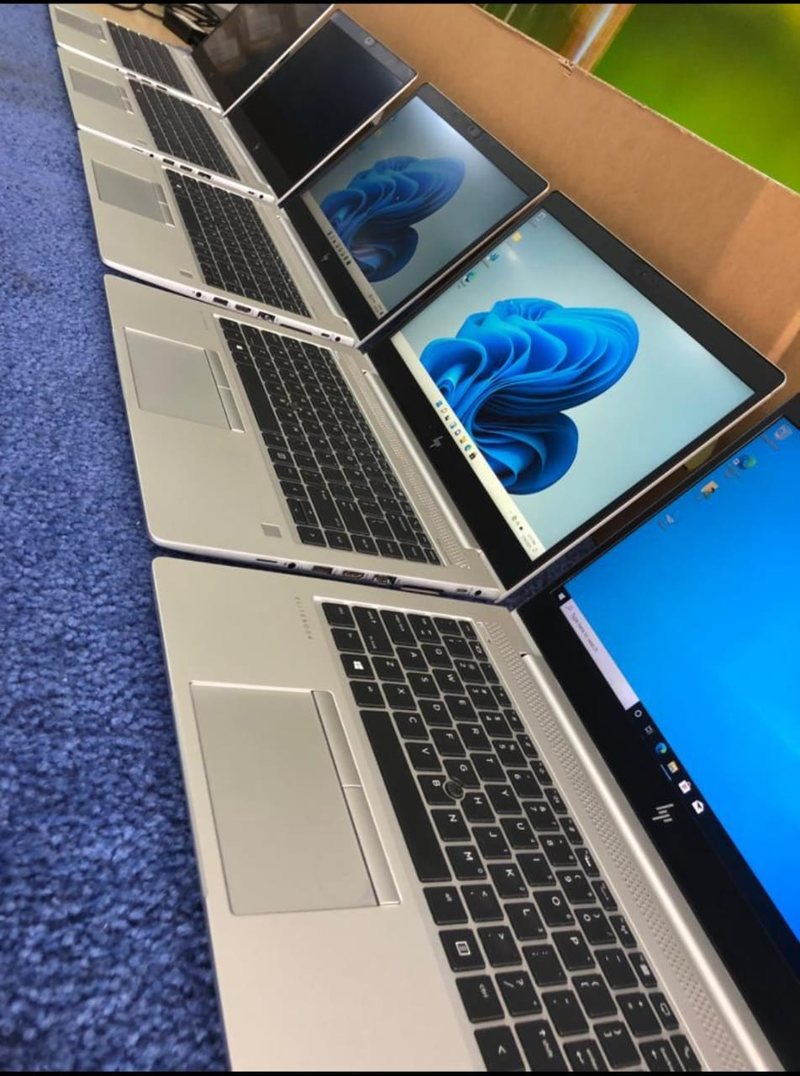 A row of HP EliteBook laptops open on a staging bench, each part-way through an operating system build.
