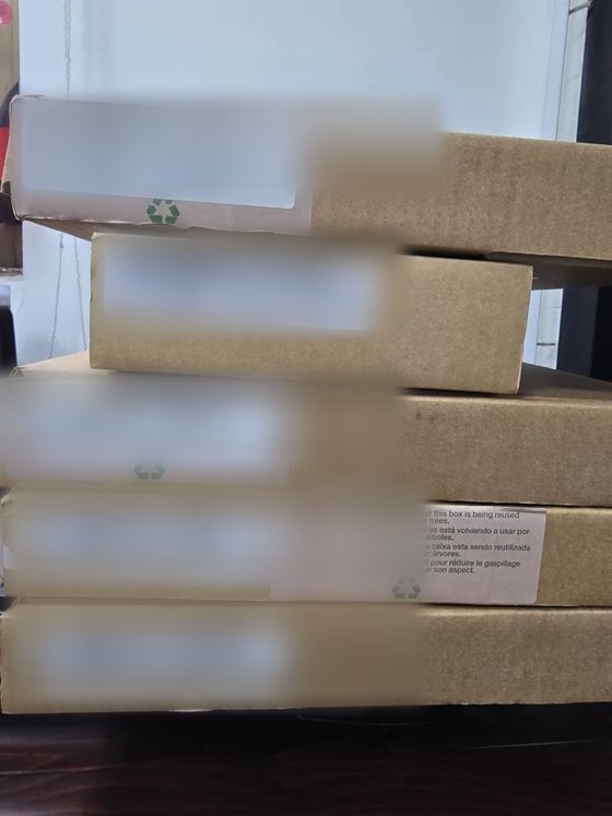 Cartons constructeur scellés empilés à la réception dans l'entrepôt Hankaka Technologies d'Accra, étiquettes masquées, préparés pour un déploiement planifié.